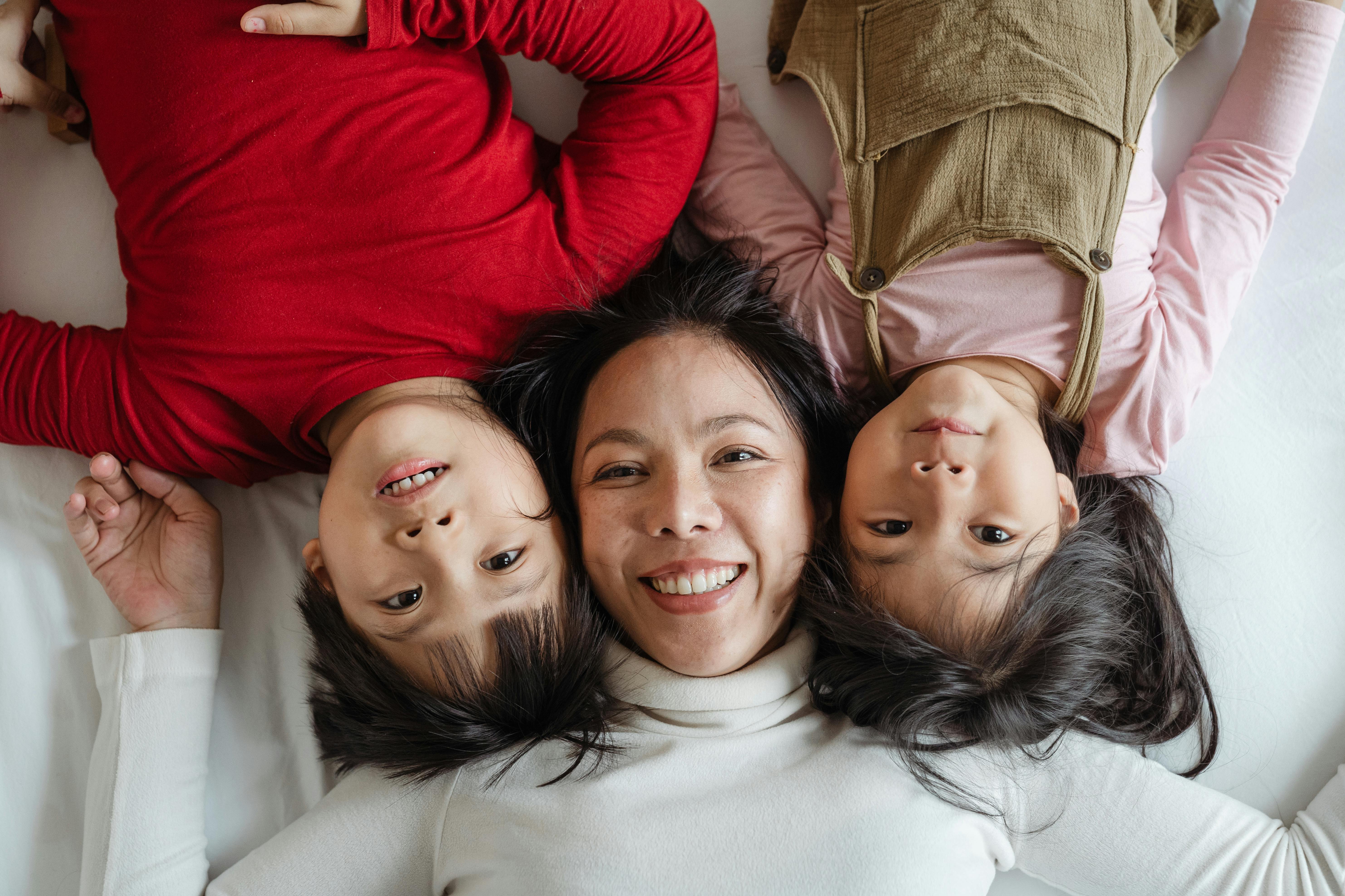 Florida working mother lying on a bed and smiling with her two young children during a quiet moment at home