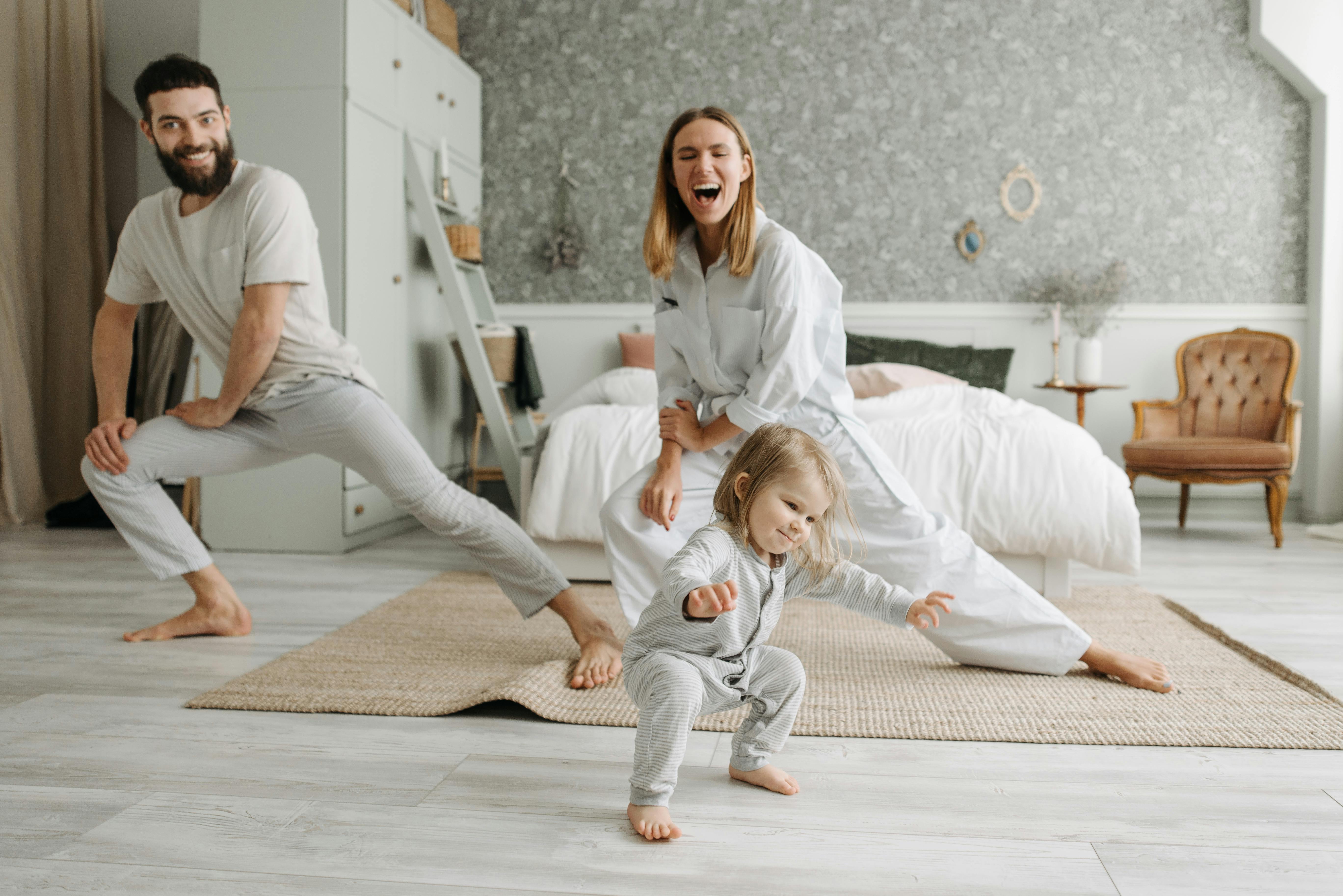 Couple stretching and exercising at home with their toddler daughter watching