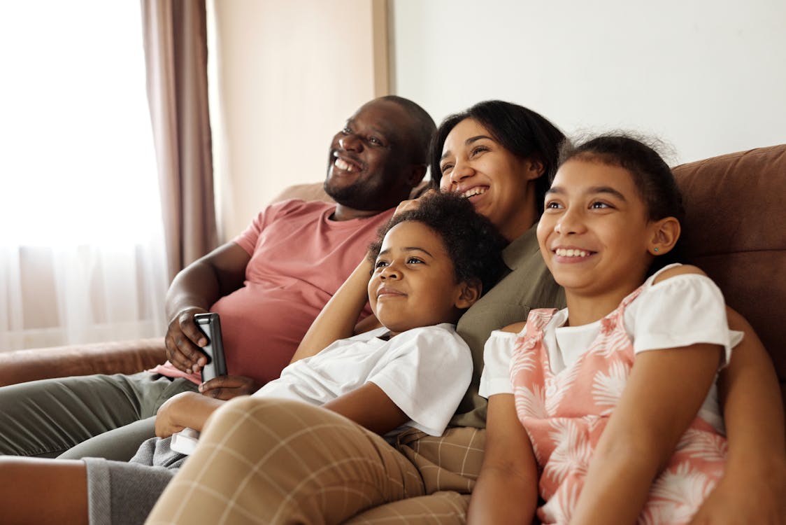 Multicultural Florida family relaxing together on a couch at home, representing the diverse households across Miami-Dade, Broward, and Orlando metro that need life insurance planning tailored to multiple cultural and faith traditions