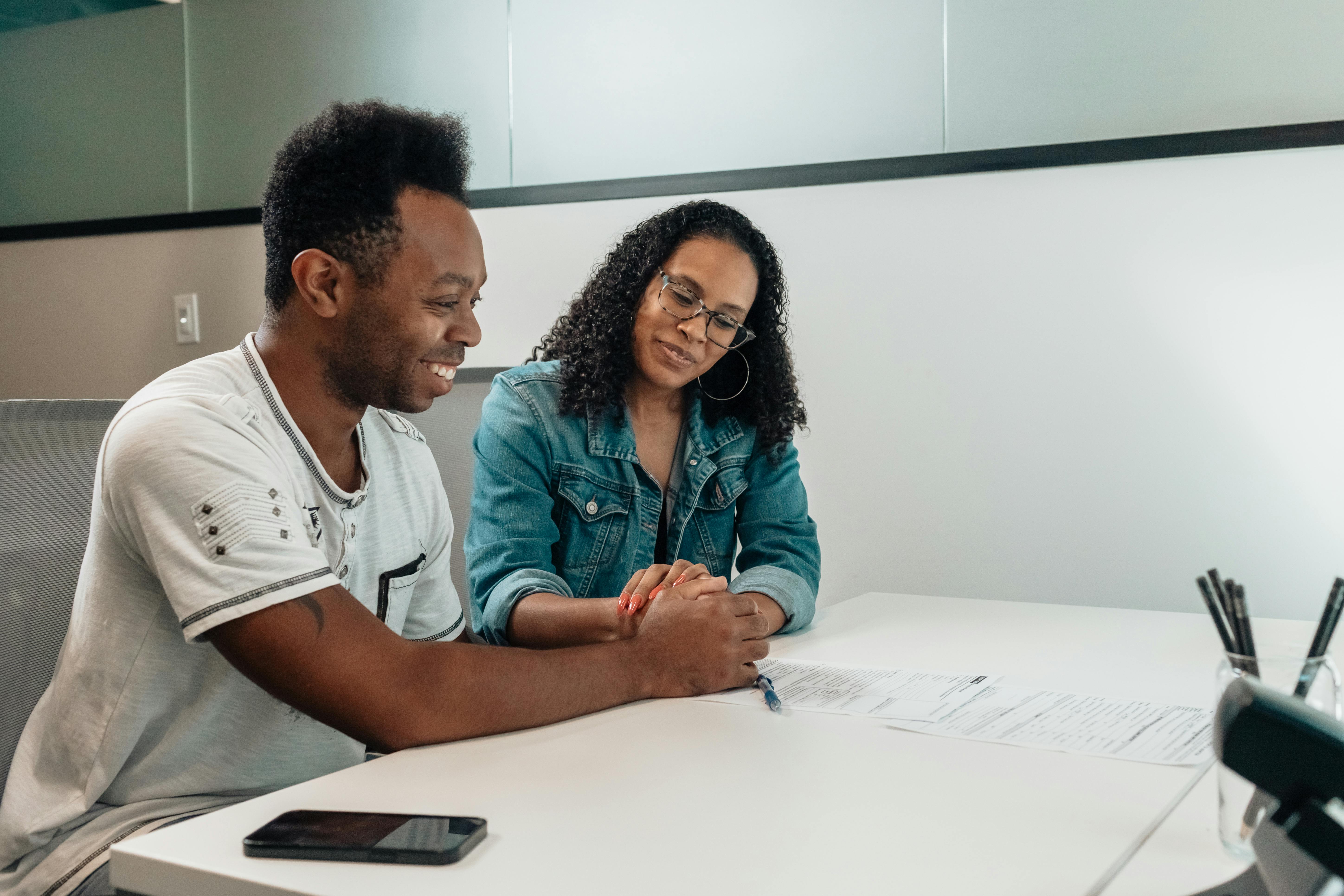 Florida couple holding hands at a desk, smiling while reviewing policy paperwork — weighing IUL vs whole life cash value growth