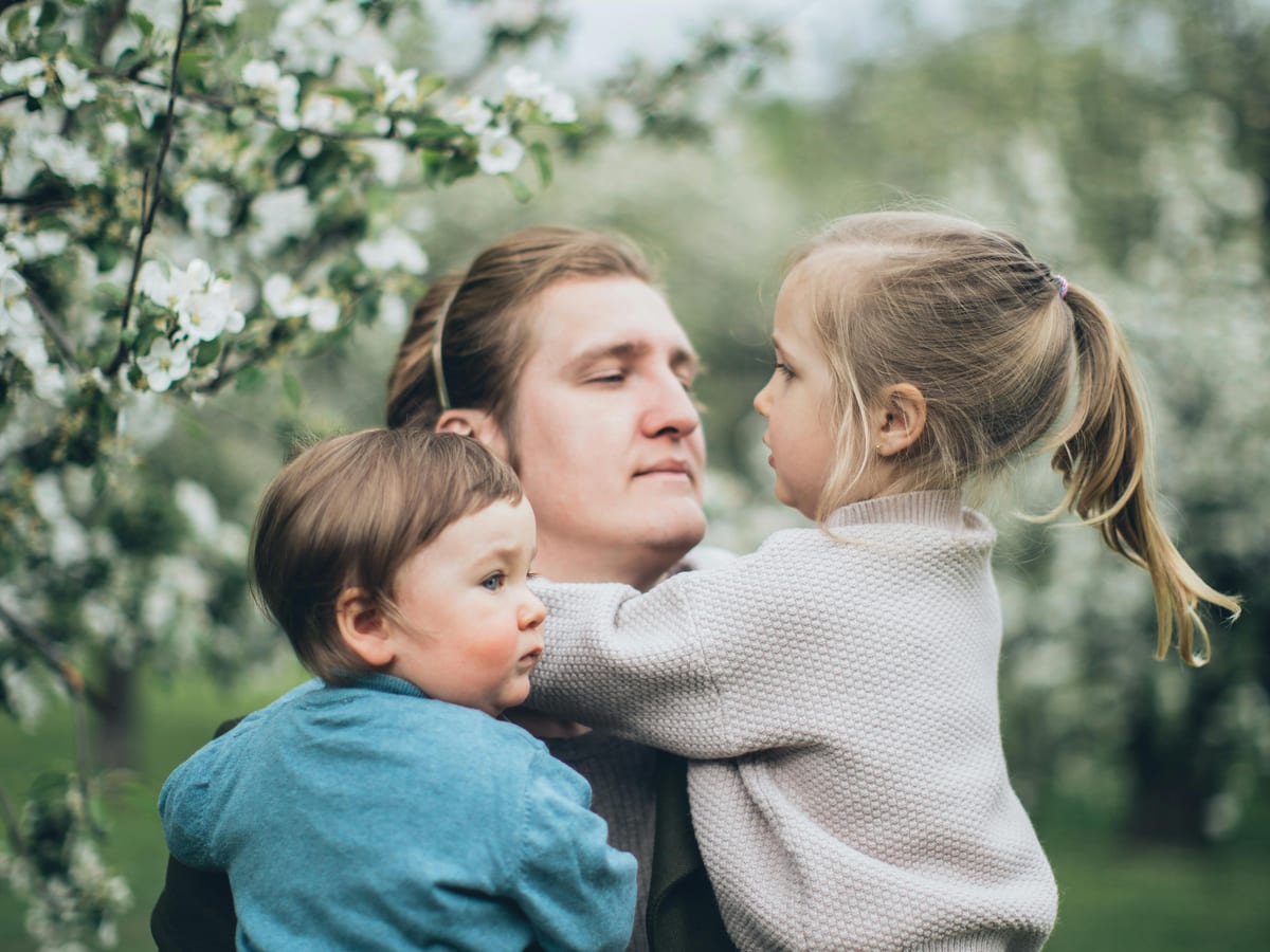 Grandfather reading a storybook to two grandchildren on a living room couch