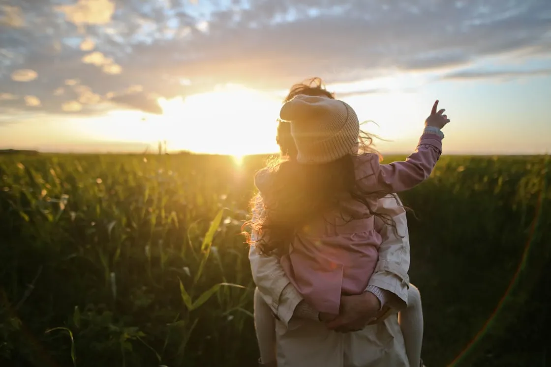 Florida single mother and her daughter embracing in a sunlit grassy field at golden hour, representing legacy and guardianship planning for solo parents