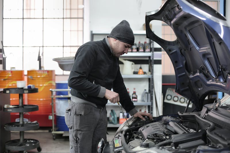 Florida auto mechanic in coveralls inspecting a car engine in a small independent garage, representing the skilled-trade workers who need occupation-aware life insurance underwriting