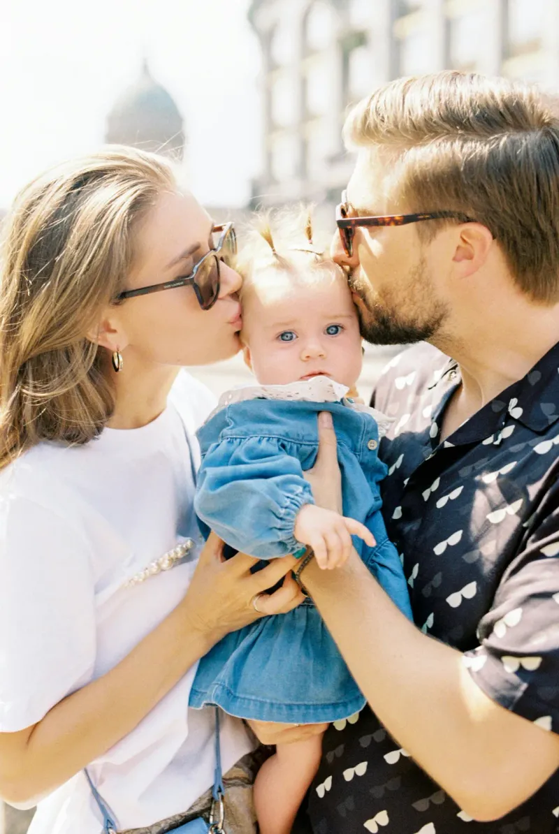 Young parents kissing their baby